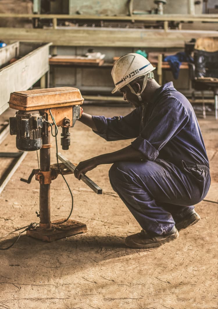 Man with hard hat operating drill press